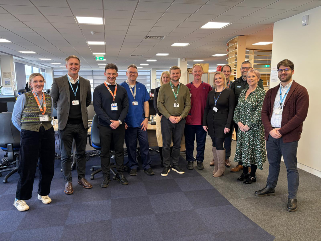 Ed with a group of eleven colleagues in an office building.
