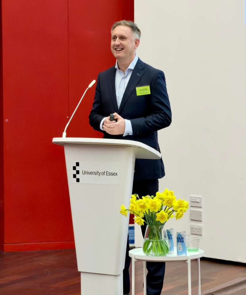 Ed speaking on stage at the EPIIC conference, presenting to attendees during a conference session.