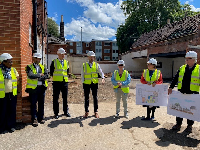 Some members of the project group working on the new Cardinal Medical Practice site are in discussion. They are outside the former Inkerman Pub and two are holding architectural drawings.