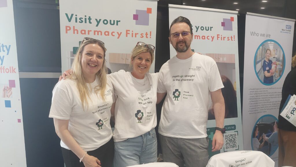 Three pharmacy colleagues in front of Pharmacy First banners