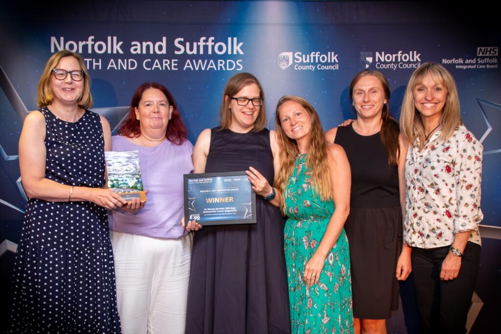 Dr Wendy McNab and team holding their certificate and award with Michaela Strachan