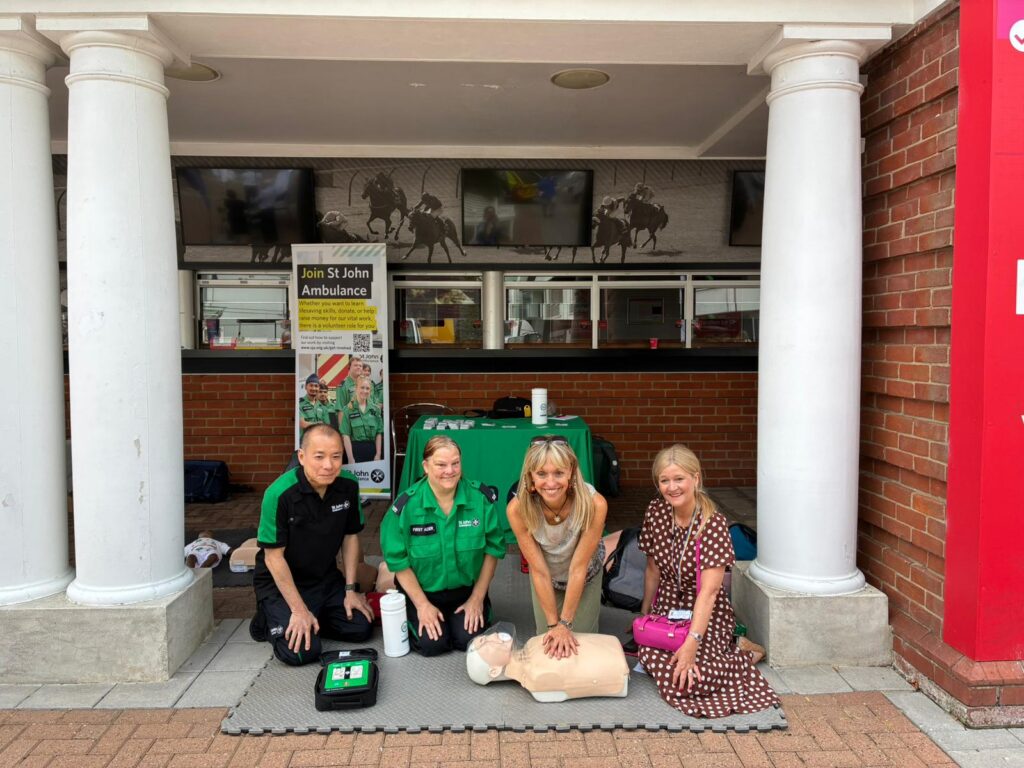 Michaela Strachan performing CPR on a dummy with St John Ambulance volunteers and Amanda Lyes, Executive Director of People, Governance and Corporate Services, NHS Norfolk and Suffolk ICB