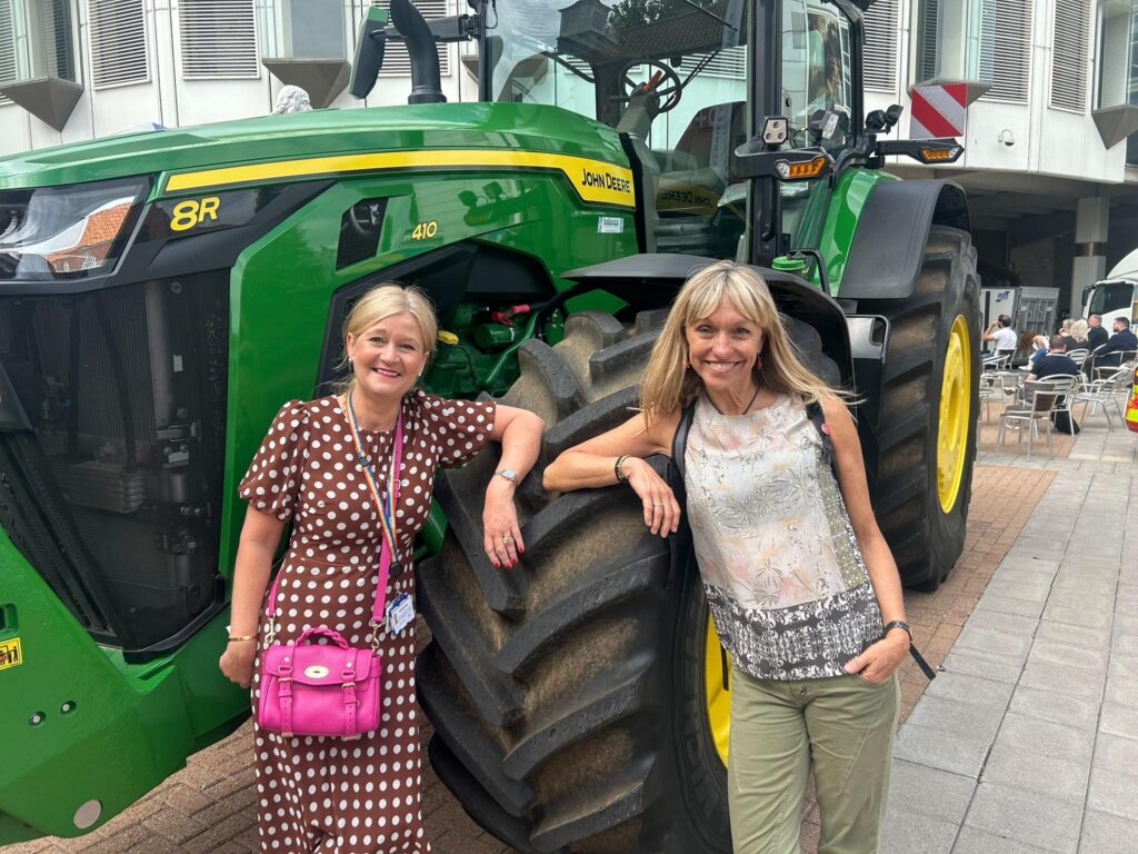 Amanda Lyes, Executive Director of People, Governance and Corporate Services at NHS Norfolk and Suffolk ICB, with Michaela Strachan in front of a tractor