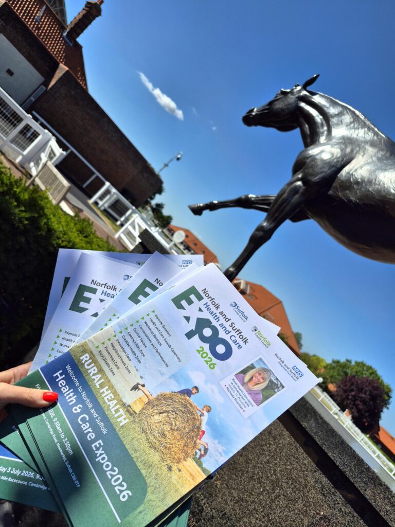 Person fanning out Expo programmes next to statue of racehorse