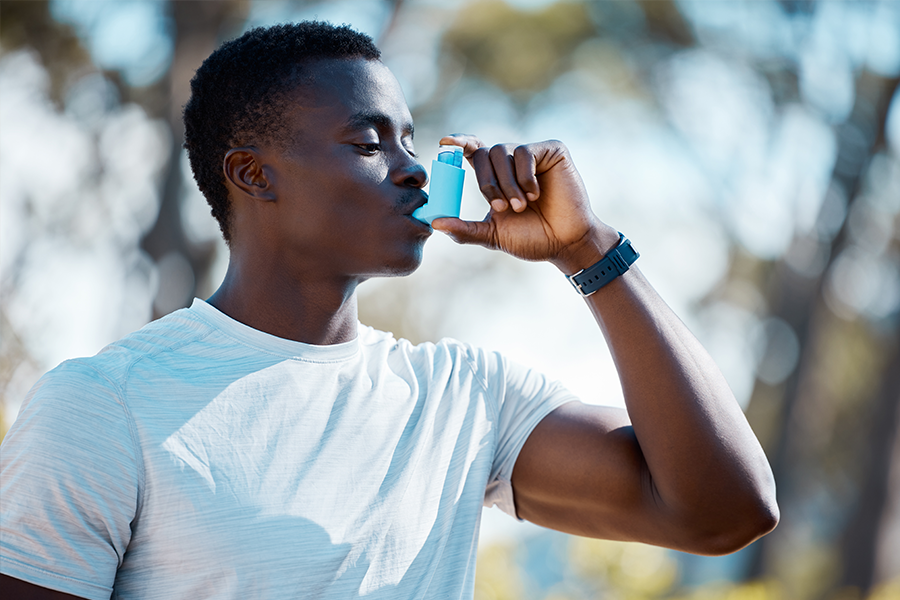 A young man using an inhaler.