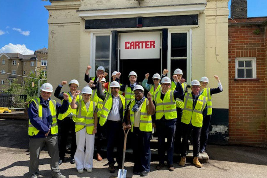 The project group in construction PPE hold their hands aloft triumphantly outside the former Inkerman Pub site. Two people are holding a spade which has broken ground, marking the start of construction.